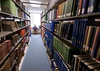 A student sitting near a row of books